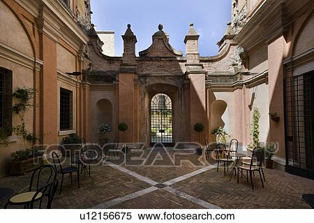 Stock Photography - Detail of inner courtyard of Italian Renaissance palazzo, with arches, windows, patterned pavimenti brick design, and ornamental wrought iron gate, brick and stucco, Todi, Umbria. Fotosearch