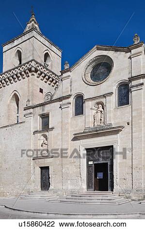 Stock Image - Detail of Romanesque facade of San Pietro Caveoso with typical stone carved scroll work and statues over decorated doorway, sunny spring afternoon, Matera, Puglia, Southern Italy. Fotosearch
