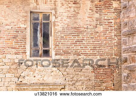 Stock Photograph - Detail of stone wall of medieval palace, with single window and decorative arch in stonework below, Todi, Umbria, Italy. Fotosearch