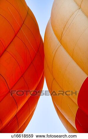 Stock Photo - Detail of two brightly coloured hot air balloons "kissing", with blue sky beyond. Fotosearch