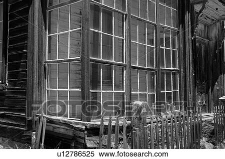 Stock Photography - Detail of wooden house with window overlooking garden and wooden picket fence, desaturated image, Bodie pioneer village, California. Fotosearch