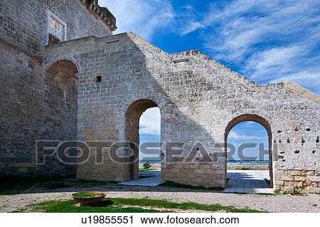 Stock Image - Detail view of Torre Lapillo, 16th century tower coastline defense, with coastline framed by arched stairway leading to square stone tower, sunny spring morning, Salento, Puglia, Southern Italy. Fotosearch