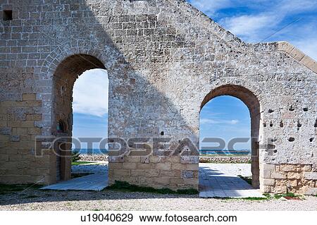 Stock Photo - Detail view of Torre Lapillo, 16th century tower coastline defense, with coastline framed by arched stairway leading to square stone tower, sunny spring morning, Salento, Puglia, Southern Italy. Fotosearch
