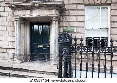 Detail view of traditional Georgian gray stone brick house with ornate column portal, blue doorway, wrought iron railing, Dublin, Southern Ireland View Large Photo Image Picture - Detail view of traditional Georgian gray stone brick house with ornate column portal, blue doorway, wrought iron railing, Dublin, Southern Ireland. Fotosearch