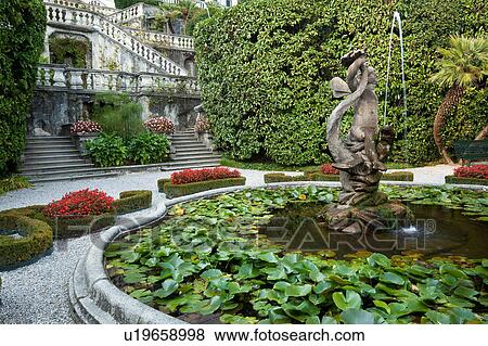 Stock Photo - Detail view of Villa Carlotta ornamental gardens, terraced stairways, fountain with statue and waterlilies, flowerbeds of red begonias, Lake Como, Northern Italy. Fotosearch