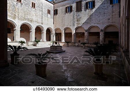 Diagonal view of cloister with frescoed loggia, central stone well, with wrought iron bucket and pulley, Romanesque Basilica of Santa Caterina, Galatina, Salento, Puglia, Southern Italy View Large Photo Image Stock Image - Diagonal view of cloister with frescoed loggia, central stone well, with wrought iron bucket and pulley, Romanesque Basilica of Santa Caterina, Galatina, Salento, Puglia, Southern Italy. Fotosearch