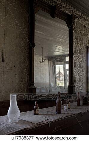 Stock Photo - Drinking saloon as seen from inside of hotel, beer bottles on bar, mirror reflecting outside street, desaturated image, Bodie pioneer village, California. Fotosearch
