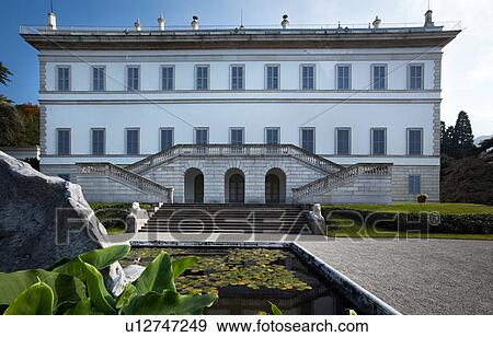 Facade of Renaissance Villa Melzi with steps to terraced bilateral stairway, flanked by lion statues, grassy slopes and fountain with waterlilies on sunny autumn afternoon, Lake Como, Northern Italy. View Large Photo Image Stock Photo - Facade of Renaissance Villa Melzi with steps to terraced bilateral stairway, flanked by lion statues, grassy slopes and fountain with waterlilies on sunny autumn afternoon, Lake Como, Northern Italy.. Fotosearch