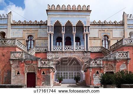 Frontal view: facade of colourful Moorish style 19th century Villa Sticchi, with stucco painted blue, orange and pink, against sunny blue sky, Santa Cesarea Terme, Salento, Puglia, Southern Italy View Large Photo Image Picture - Frontal view: facade of colourful Moorish style 19th century Villa Sticchi, with stucco painted blue, orange and pink, against sunny blue sky, Santa Cesarea Terme, Salento, Puglia, Southern Italy. Fotosearch