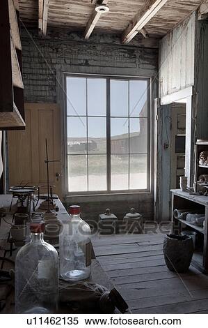 Stock Photography - Hotel: part of kitchen, storage room with artefacts, and street seen through window, desaturated image, Bodie pioneer village, California. Fotosearch