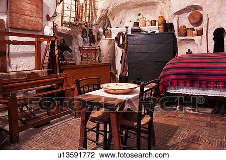 Interior of house built into tufa cavern, showing bed, table, chairs, weaving loom, and antique implements representational of traditional life in Matera, Puglia, Southern Italy View Large Photo Image Stock Image - Interior of house built into tufa cavern, showing bed, table, chairs, weaving loom, and antique implements representational of traditional life in Matera, Puglia, Southern Italy. Fotosearch