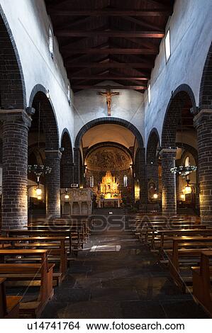Picture - Interior of Romanesque church of San Giacomo showing side nave with stone columns and arches, wooden ceiling and illuminated altar, Bellagio, Lake Como, Northern Italy. Fotosearch
