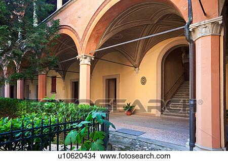 Picture - Internal courtyard of Renaissance palazzo with shrubs and trees beyond wrought iron railing, and view of stylish portico entrance, Bologna Italy. Fotosearch