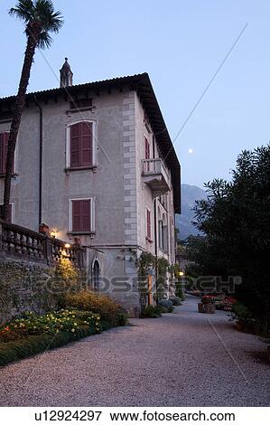 Ornamental gardens and pathway in Villa Monastero with terracotta pots on columns, flower beds, and villa annex, autumn evening at dusk with moonrise and blue sky, Northern Italy View Large Photo Image Stock Photo - Ornamental gardens and pathway in Villa Monastero with terracotta pots on columns, flower beds, and villa annex, autumn evening at dusk with moonrise and blue sky, Northern Italy. Fotosearch