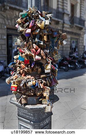 Padlocks fastened to chain on lamp post, multicoloured, against background of motorbikes parked outside Renaissance palazzo behind, Lecce, Salento, Puglia, Southern Italy View Large Photo Image Stock Photo - Padlocks fastened to chain on lamp post, multicoloured, against background of motorbikes parked outside Renaissance palazzo behind, Lecce, Salento, Puglia, Southern Italy. Fotosearch