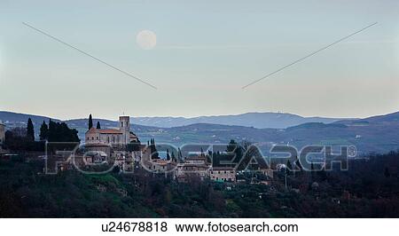 Stock Photo - Panorama of hilltop town of Monte Mulino, near Todi, with deserted castle in foreground, with distant hills and pink skyscape, full moon rising, Umbria, Italy. Fotosearch