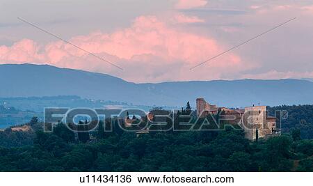 Stock Photograph - Panorama of hilltop town of Monte Mulino, near Todi, with deserted castle in foreground, with distant hills and pink skyscape, Umbria, Italy. Fotosearch