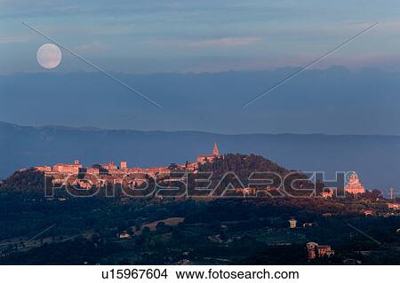 Picture - Panorama view of full moon rising over medieval hilltop town of Todi, with spire of San Fortunato, and Tempio of Bramante, Umbria, Italy. Fotosearch