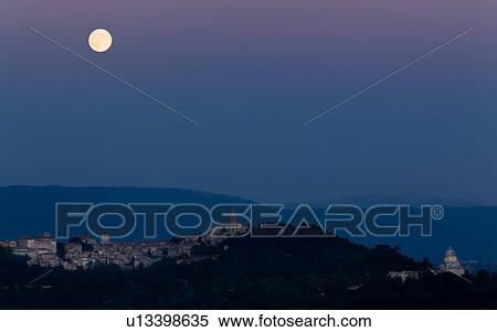 Panorama view of full moon rising over medieval hilltop town of Todi, with spire of San Fortunato, and Tempio of Bramante, town lights illuminated at dusk, Umbria, Italy View Large Photo Image Stock Photography - Panorama view of full moon rising over medieval hilltop town of Todi, with spire of San Fortunato, and Tempio of Bramante, town lights illuminated at dusk, Umbria, Italy. Fotosearch