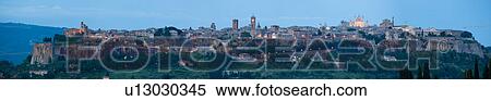 Stock Photography - Panorama view of Orvieto city skyline at dusk, with duomo facade lit by setting sun, Italy. Fotosearch
