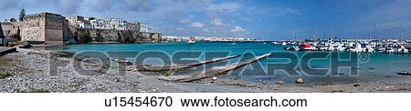 Stock Image - Panorama view of Otranto harbour with moored sailboats and motorboats, medieval fortifications and town, sunny spring morning with blue sky, Salento, Puglia, Southern Italy. Fotosearch