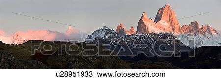 Panorama view of sunrise over the snow covered Andes mountain range, El Chalten, Argentina, Patagonia, with clear blue sky, and mountains of Mount Fitzroy and Cerro Torre reflecting red light of rising sun View Large Photo Image Stock Image - Panorama view of sunrise over the snow covered Andes mountain range, El Chalten, Argentina, Patagonia, with clear blue sky, and mountains of Mount Fitzroy and Cerro Torre reflecting red light of rising sun. Fotosearch