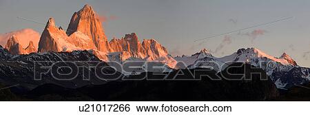Panorama view of sunrise over the snow covered Andes mountain range, El Chalten, Argentina, Patagonia, with clear blue sky, and mountains of Mount Fitzroy and Cerro Torre reflecting red light of rising sun View Large Photo Image Stock Photograph - Panorama view of sunrise over the snow covered Andes mountain range, El Chalten, Argentina, Patagonia, with clear blue sky, and mountains of Mount Fitzroy and Cerro Torre reflecting red light of rising sun. Fotosearch