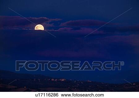Stock Photograph - Panoramic view of full moon rising over rolling Umbrian hills. Fotosearch