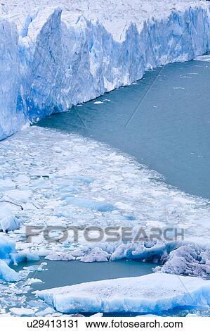 Stock Image - Perito Moreno Glacier, early morning, cloudy autumn day, blue ice detail and fallen ice floating in Lago Argentino, Los Glaciares, Argentina, Patagonia. Fotosearch