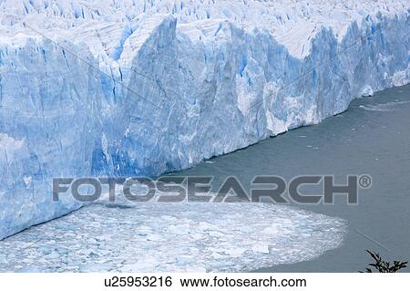 Stock Photograph - Perito Moreno Glacier, early morning, cloudy autumn day, blue ice detail and fallen ice floating in Lago Argentino, Los Glaciares, Argentina, Patagonia. Fotosearch