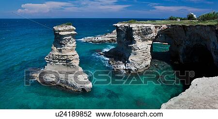 Rocky coastline and natural arch formation of sea stacks, clear blue sea on sunny spring morning, 2 fishermen on rocks in distance, Salento, Puglia, Southern Italy View Large Photo Image Stock Image - Rocky coastline and natural arch formation of sea stacks, clear blue sea on sunny spring morning, 2 fishermen on rocks in distance, Salento, Puglia, Southern Italy. Fotosearch