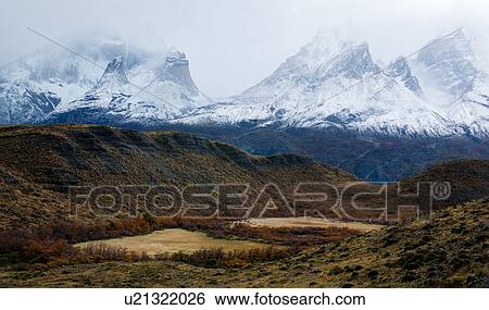 Stock Photograph - Snow covered mountains Los Cuernos, panorama view with autumn colours of trees and calafate shrubs, near Lake Nordenskjold, Torres del Paine, Southern Chile, Patagonia. Fotosearch