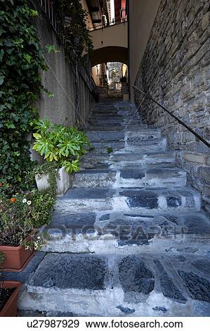 Steep uneven stone stairway up narrow alley with stone walls of houses, typical evocative style of Northern Italy View Large Photo Image Stock Photo - Steep uneven stone stairway up narrow alley with stone walls of houses, typical evocative style of Northern Italy. Fotosearch