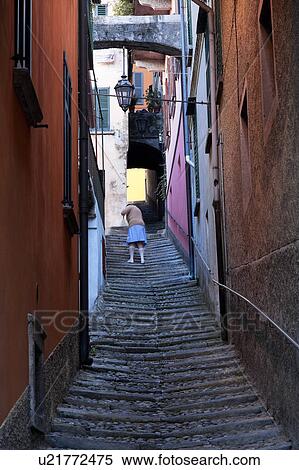 Steep uneven stone stairway up narrow alley with walls of houses painted red/orange in typical evocative style of Northern Italy, woman sweeping stairs with broom. View Large Photo Image Stock Photography - Steep uneven stone stairway up narrow alley with walls of houses painted red/orange in typical evocative style of Northern Italy, woman sweeping stairs with broom.. Fotosearch