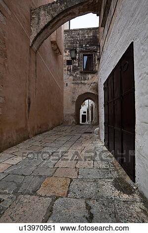 Street in Ostuni, with typical white stucco walls, stone paving, wrought iron lamp, and archway, spring afternoon, Salento, Puglia, Southern Italy View Large Photo Image Stock Image - Street in Ostuni, with typical white stucco walls, stone paving, wrought iron lamp, and archway, spring afternoon, Salento, Puglia, Southern Italy. Fotosearch