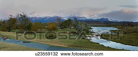 Sunrise view of snow covered mountain range and River Serrano, Torres del Paine, with pink and grey clouds, beech trees in full autumn colours, Southern Chile, Patagonia View Large Photo Image Stock Image - Sunrise view of snow covered mountain range and River Serrano, Torres del Paine, with pink and grey clouds, beech trees in full autumn colours, Southern Chile, Patagonia. Fotosearch