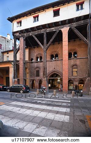View across street pedestrian crossing showing medieval palazzo Casa Isolani, with Y-shaped oak beams holding up third floor and forming portico below, sunny late summer afternnoon, Bologna, Italy View Large Photo Image Stock Photo - View across street pedestrian crossing showing medieval palazzo Casa Isolani, with Y-shaped oak beams holding up third floor and forming portico below, sunny late summer afternnoon, Bologna, Italy. Fotosearch