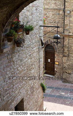 Stock Photo - View from above of stone paved street with medieval stone buildings lining each side, and connecting arch above, on sunny afternoon, Assisi, Umbria, Italy. Fotosearch