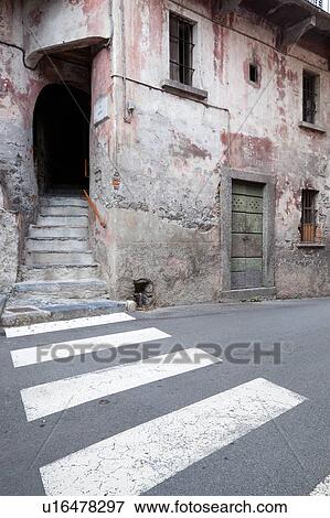 View of Italian village street with pedestrian crossing leading to stairway, and view of delapidated house wih fading pink paintwork on stone and stucco, old green wooden door, Northern Italy View Large Photo Image Stock Photo - View of Italian village street with pedestrian crossing leading to stairway, and view of delapidated house wih fading pink paintwork on stone and stucco, old green wooden door, Northern Italy. Fotosearch