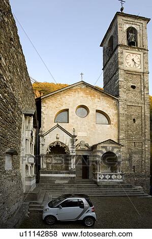 View of medieval church front facade and bell tower across tiny piazza with single modern Italian car parked in front of entrance steps and adjacent ancient stone wall, Lake Como, Northern Italy View Large Photo Image Stock Photo - View of medieval church front facade and bell tower across tiny piazza with single modern Italian car parked in front of entrance steps and adjacent ancient stone wall, Lake Como, Northern Italy. Fotosearch