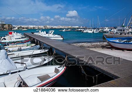 View of Otranto harbour with moored sailboats and motorboats, medieval fortifications and town beyond, sunny spring morning with blue sky, Salento, Puglia, Southern Italy View Large Photo Image Stock Photograph - View of Otranto harbour with moored sailboats and motorboats, medieval fortifications and town beyond, sunny spring morning with blue sky, Salento, Puglia, Southern Italy. Fotosearch