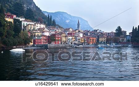 View over lake of town of Varenna along lake shore with mountain range beyond on calm autumn afternoon in pale sunlight, Lake Como, Northern Italy View Large Photo Image Stock Image - View over lake of town of Varenna along lake shore with mountain range beyond on calm autumn afternoon in pale sunlight, Lake Como, Northern Italy. Fotosearch