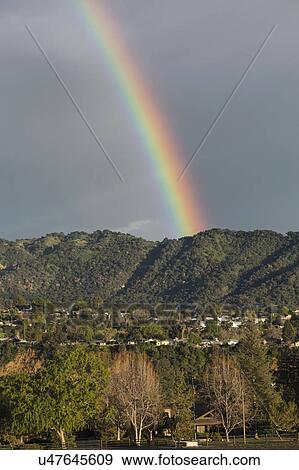 Stock Photo - Oak View, California, USA, March 1, 2015, full rainbow over rain storm over mountains Ojai Valley. Fotosearch