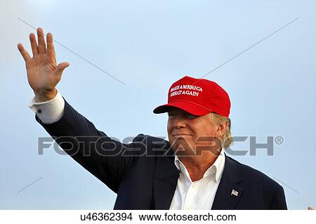 Picture - SAN PEDRO, CA - SEPTEMBER 15, 2015: Donald Trump, 2016 Republican presidential candidate, waves during a rally aboard the Battleship USS Iowa in San Pedro, Los Angeles, California while wearing a red baseball hat that says campaign slogan "Make.... Fotosearch