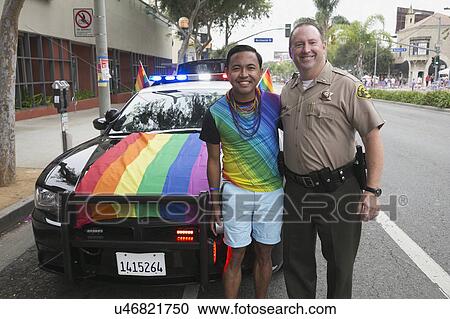 Stock Image - West Hollywood, Los Angeles, California, USA, June 14, 2015, 40th annual Gay Pride Parade for LGBT Community, down Santa Monica Blvd., LA Police Dept. with Rainbow LGBT flag on car poses with gay male. Fotosearch