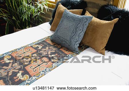 Stock Photo - Bed runner and throw pillows on bed. Fotosearch