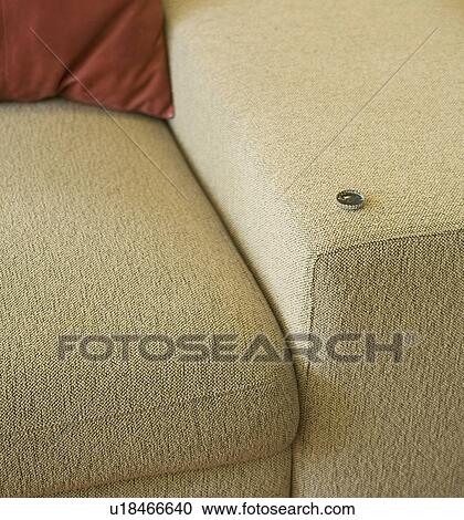 Stock Image - Beer cap on arm of sofa. Fotosearch