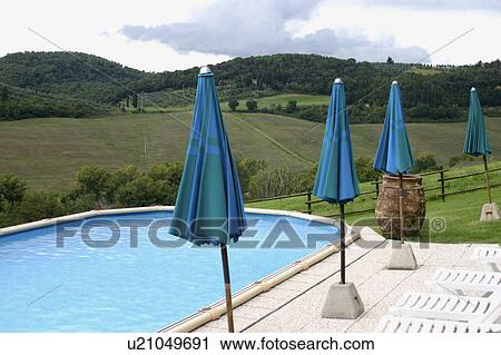 Stock Image - Blue umbrellas along poolside. Fotosearch