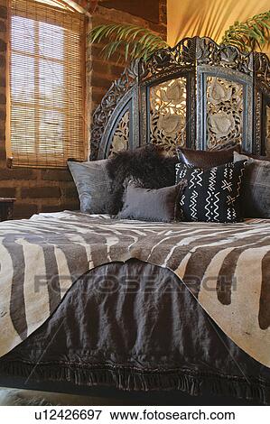 Stock Photo - Brown African printed bedding on bed. Fotosearch