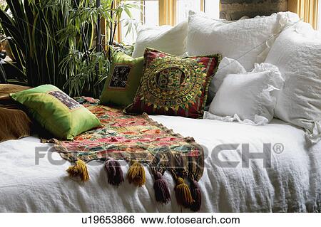 Stock Photograph - Colorful bed runner and throw pillows on bed. Fotosearch